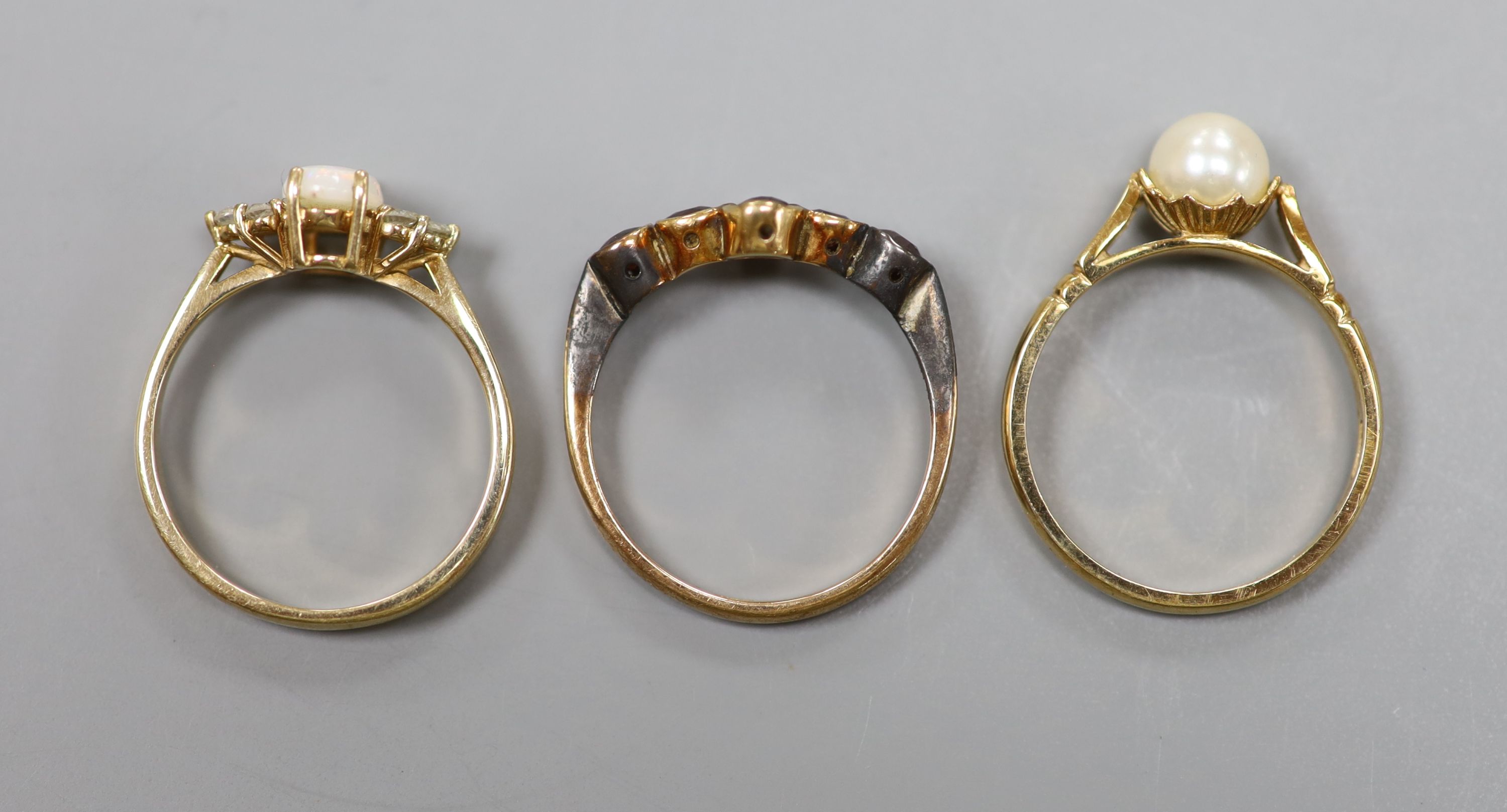 A 9ct yellow gold garnet-set ring, a similar cabochon opal and small diamond ring and a similar pearl-set ring (3) 6.5g